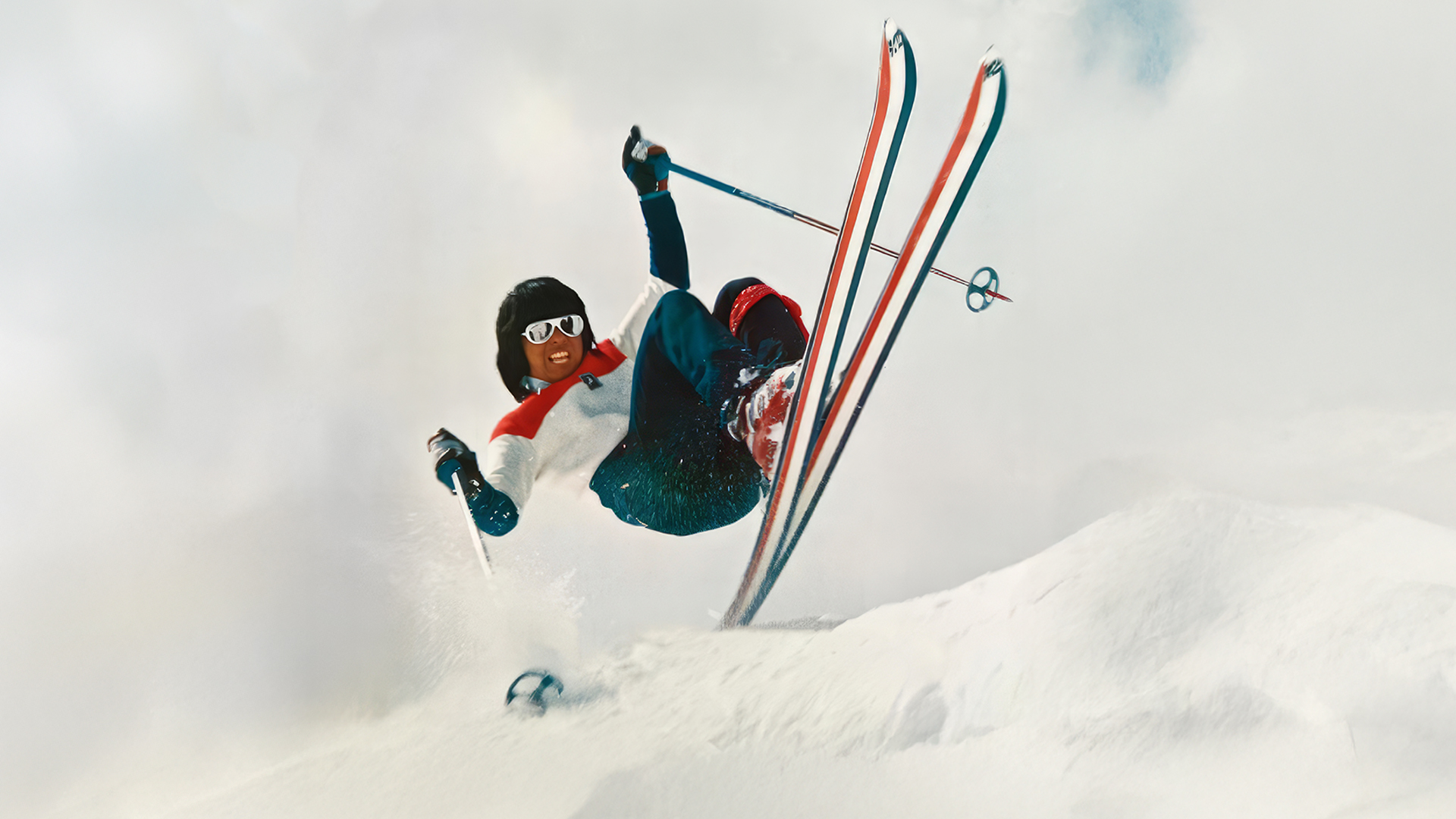 Wayne Wong airborne on skis against a snowy mountain backdrop