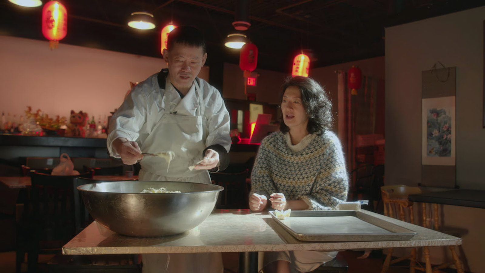 Jackie Kai Ellis cooking with a guest in a restaurant