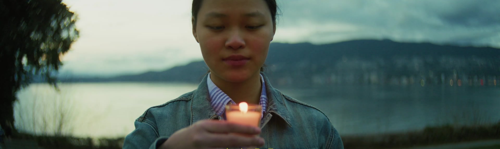 A fan holding a candle beside the water in Vancouver
