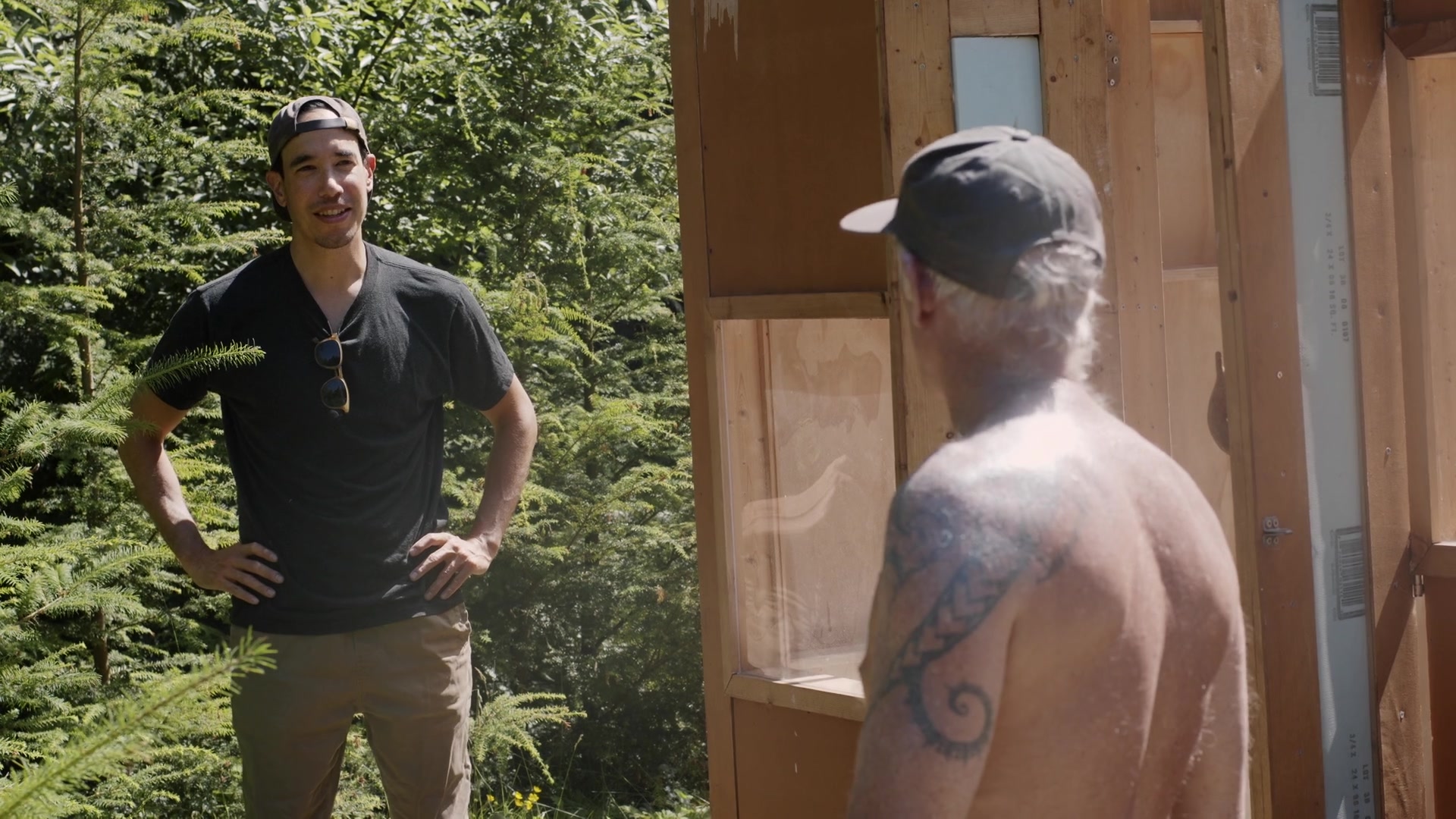 Danny speaking with a member outside a wooden cabin