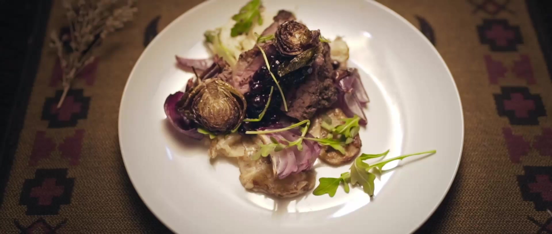 A finished dish plated with vegetables and greens